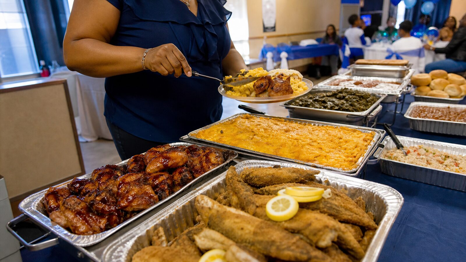 K&C Sparkles team member serving fried fish, chicken, macaroni and cheese and sides from a catering spread at an event styled in blue and white